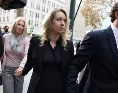 Holmes (no centro) junto com o marido e a mãe dela enquanto entravam no tribunal.