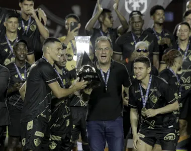 Osvaldo (direita) celebra a taça de campeão ao lado do presidente Fábio Mota e de outros jogadores