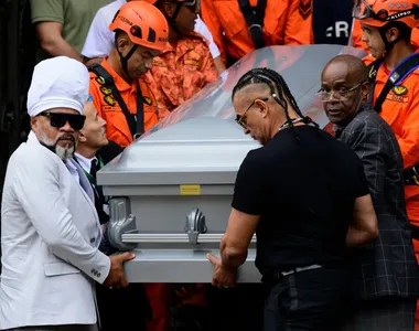 Caixão de Preta Gil sendo conduzido por Carlinhos Brown e bombeiros