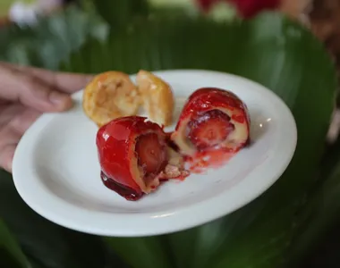 Na foto, um morango do amor e uma bala de vidro, de sabor tradicional