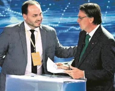 Carlos Bolsonaro ao lado de Jair Bolsonaro durante um debate das eleições em 2022