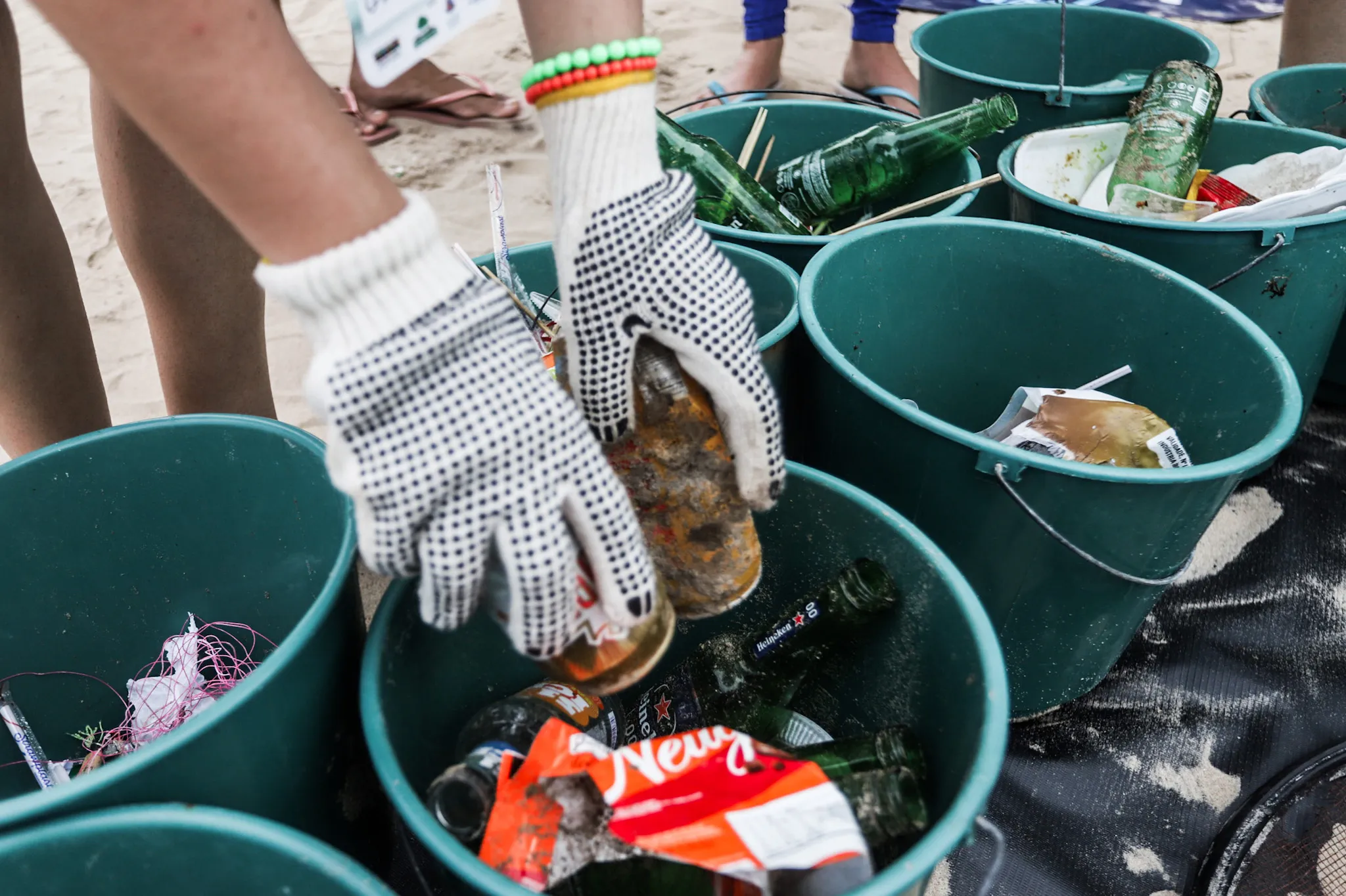 Mão de voluntário separando lixo encontrado na Praia de Piatã