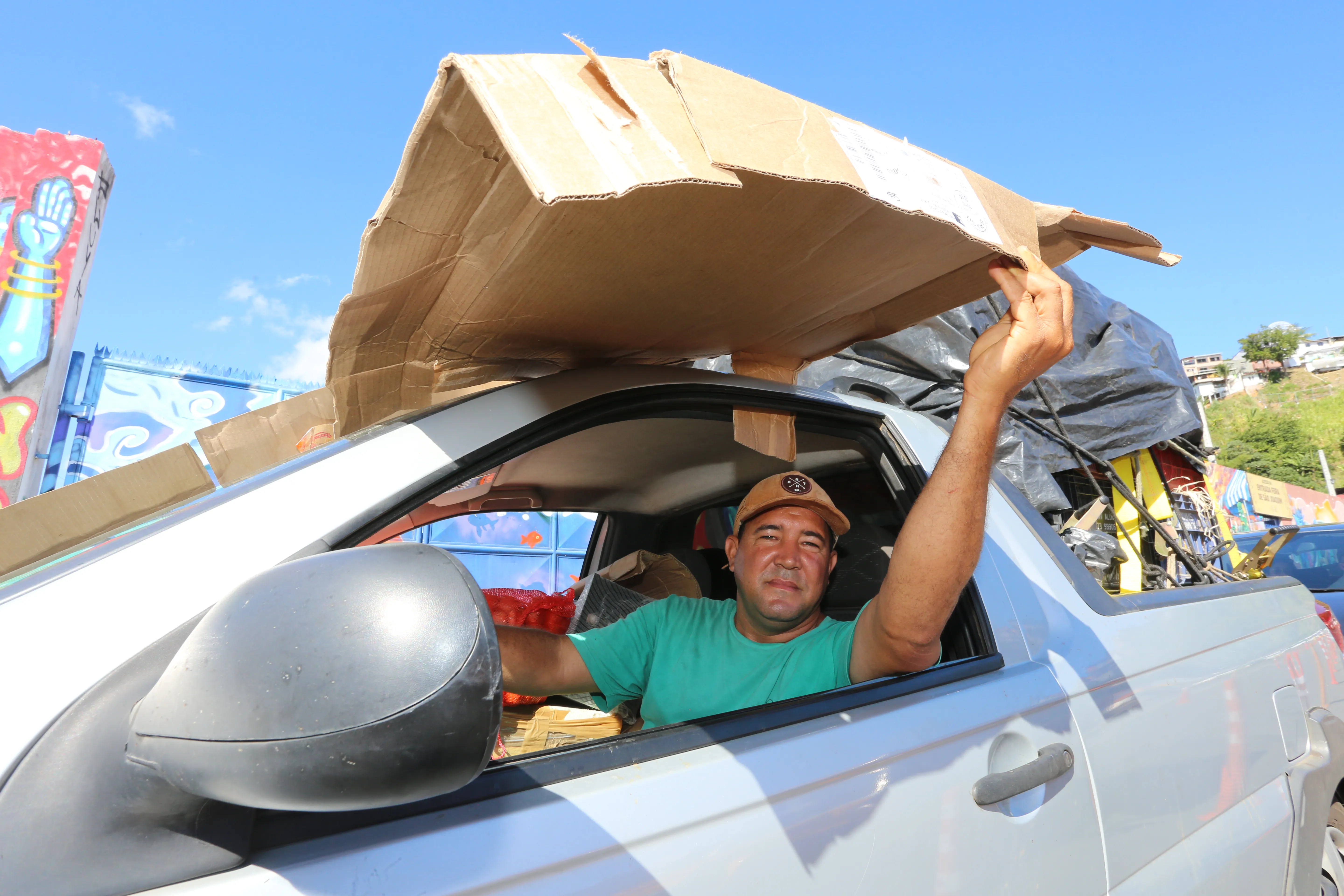 Comerciante Rogério Araújo improvisou um papelão para se proteger do sol, estava na fila há mais desde às 10h30 da manhã;