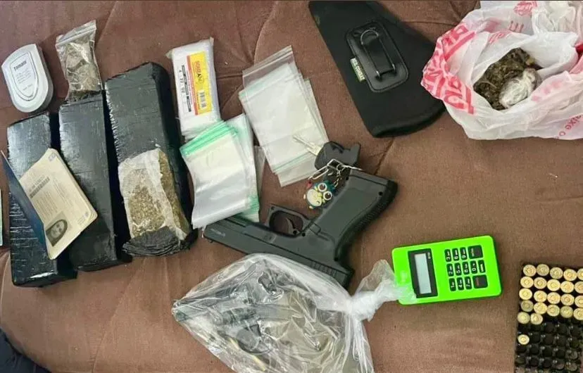 As autoridades encontraram uma pistola, porções de drogas, embalagens, uma máquina de cartão de crédito, réplica de arma e munições.